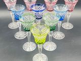six different colored glass wine glasses sitting on top of a table