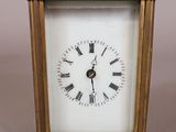 a small gold clock with roman numerals on it