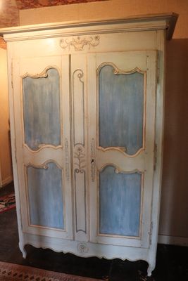 a white armoire with blue glass doors in the corner of a room