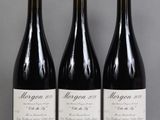 trois bouteilles de vin rouge sont alignées sur une table