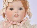 a doll that is wearing a white dress and a pink hat