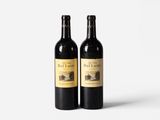 two bottles of red wine sitting next to each other on a white surface