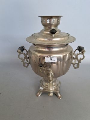 une théière ancienne en métal argenté, avec couvercle, posée sur un socle
