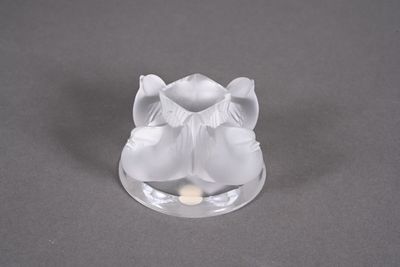 un petit bougeoir en verre surmonté d'une fleur