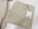 a knitted sweater with a tag on it next to a pair of shoes