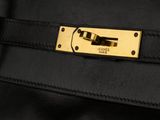 a close up of a black leather handbag with gold hardware