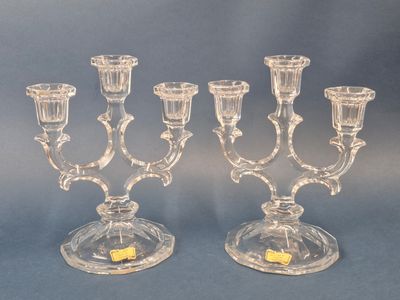 two clear glass candelabs with candles on a blue background