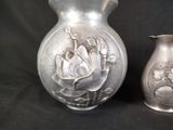 a silver vase and a silver vase sitting next to each other