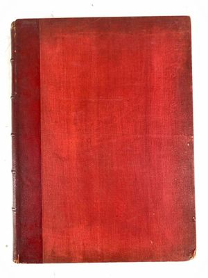 un vieux livre à la couverture rouge posé sur une surface blanche