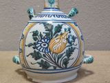 a blue and white vase with a yellow flower on it