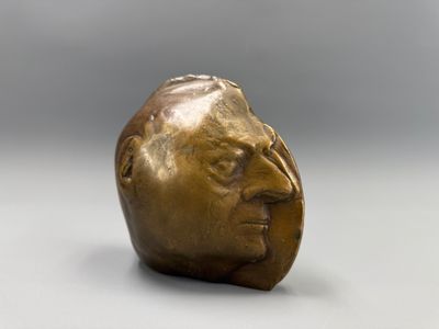 une vieille tête d'homme en bronze posée sur un fond blanc