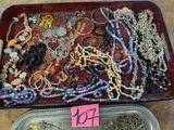 a tray full of assorted beads and necklaces on a table