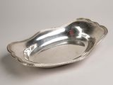 an antique silver plate with a red bead on the edge