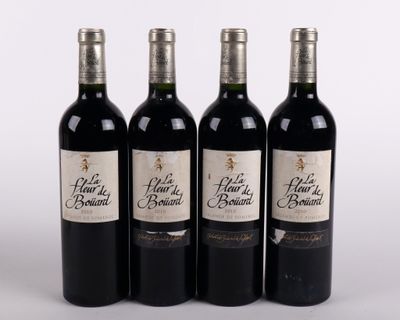 quatre bouteilles de vin sont alignées sur une surface blanche