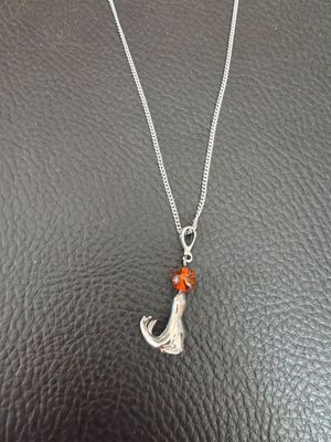 a silver necklace with a cat charm on it sitting on a black surface