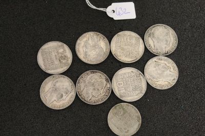 several silver coins are arranged in a triangle on a black surface