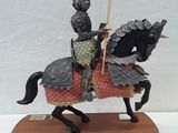 figurine of a knight on a horse with a flag on a wooden base