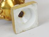 a gold and white vase sitting on a white surface