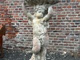 une statue représentant une femme tenant un bol sur la tête
