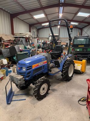 a blue tractor parked in a garage with other vehicles