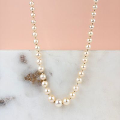 a close up of a pearl necklace on a marble surface