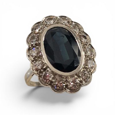 une image représentant une bague ornée d'une grosse pierre noire entourée de petits diamants blancs