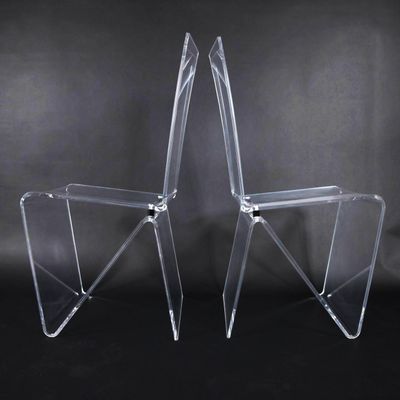 pair of clear acrylic chairs against a black background
