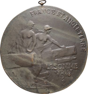 une vieille médaille en argent représentant un homme et une femme assis sur un banc