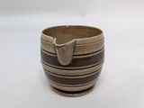 a brown and black bowl on a white surface