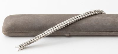 an image of a silver bracelet laying on top of a gray case