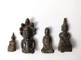 cinq petites statues de bouddhas posées sur une surface blanche