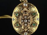 a close up of a gold locke with diamonds and emeralds