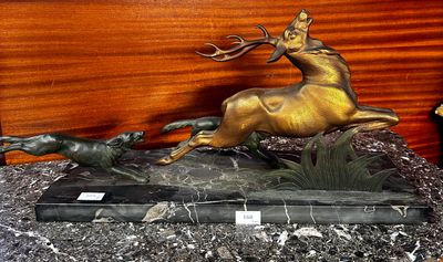 une statue en bronze représentant un cerf et un chien en pleine course, posée sur un socle en marbre