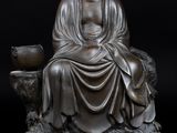 statue d'un Bouddha assis sur un rocher, tenant un bol dans la main