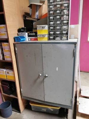 a metal cabinet in the middle of a room with a pink wall