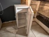 a small white refrigerator in the corner of a kitchen