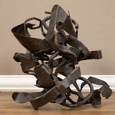 une sculpture en métal posée sur un plancher en bois