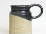 a black and white mug with a handle on a white surface