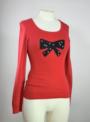 pull rouge orné d'un nœud noir sur les épaules