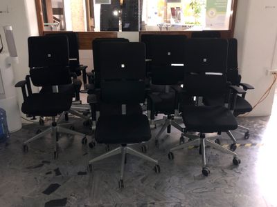 six chaises de bureau noires dans une pièce avec une fenêtre en arrière-plan