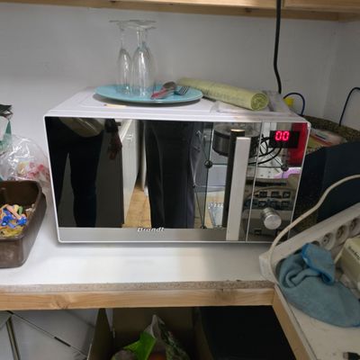 a microwave that is sitting on a shelf in the kitchen