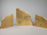 two gold bookends on a white surface with a gray background
