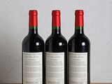 trois bouteilles de vin posées sur une table en bois à côté d'une bouteille de vin