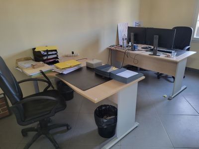 a desk with two computers and a chair in the corner