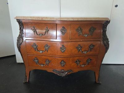a wooden dresser with a marble top on a black floor