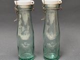 paire de salières et poivrières en verre vert avec des couvercles blancs