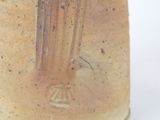 a brown and white vase with a fork sticking out of it