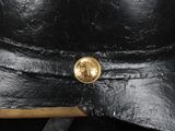 a close up of a black hat with a gold button on it