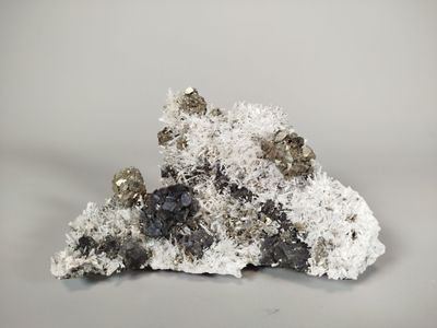 some white and black crystals are sitting on top of a piece of rock