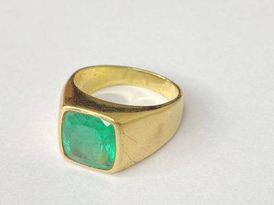 an image of a gold ring with a green stone on it